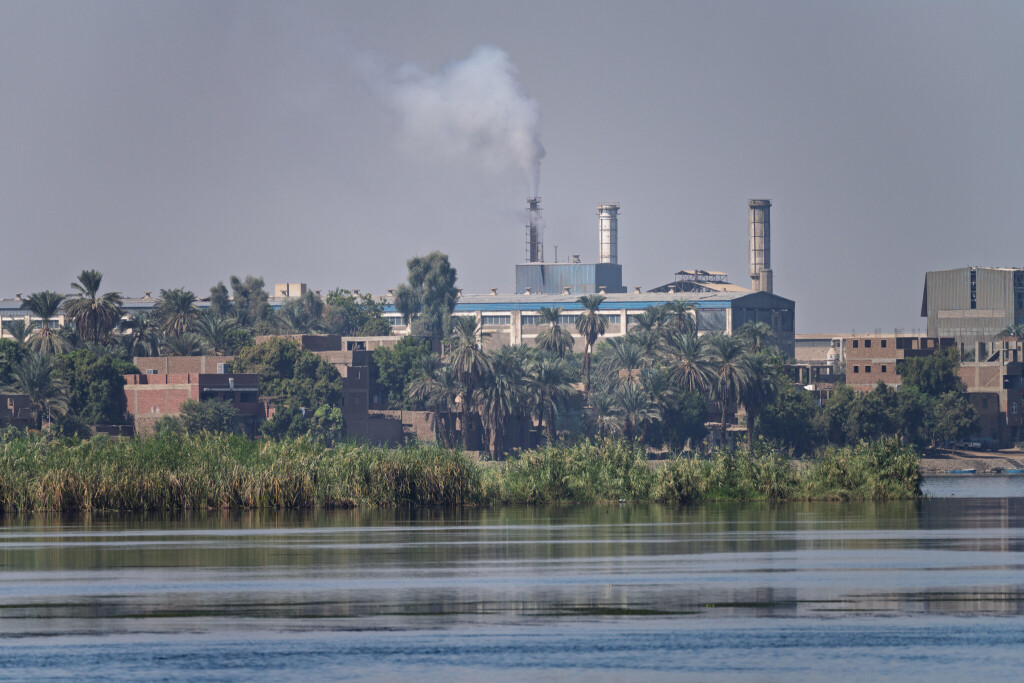 Das Stahlwerk von Edfu in Ägypten mit seinen Industriegebäuden und Schornsteinen, vom Nil aus gesehen. 6. November 2024